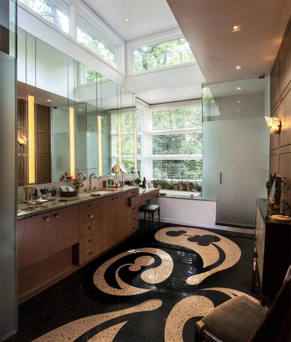 Primary bathroom with custom wood cabinetry, mirrored walls, clerestory windows, and graphic terrazzo flooring